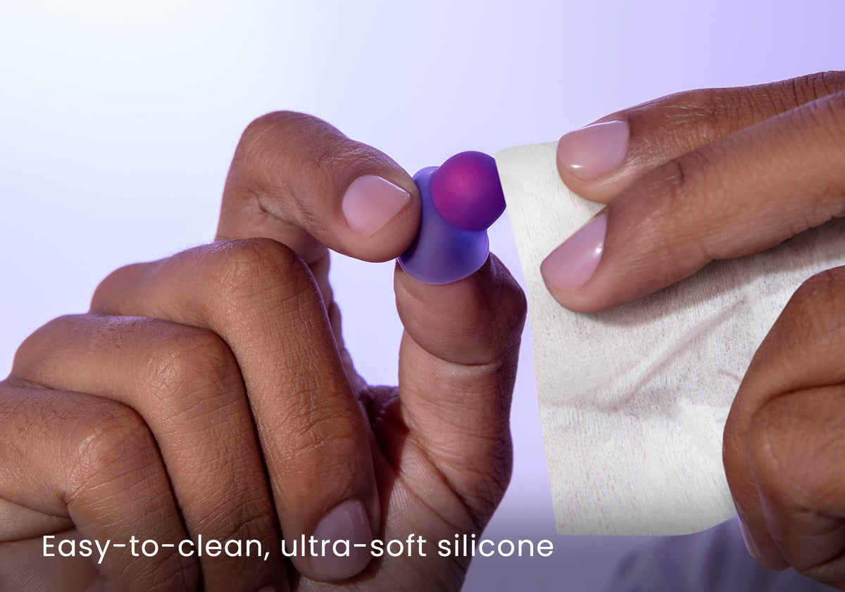 Close-up of hands wiping a purple Manta Sleep earplug with a white tissue, captioned "Easy-to-clean, ultra-soft silicone".